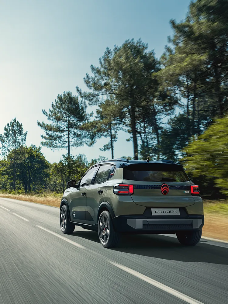Rear three-quarter view Citroën C3 Outdoor with LED taillights shows Advanced Comfort compact SUV on open road