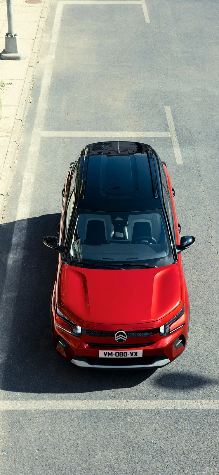 Overhead front view of the Citroën ë-C3 Van driving in an urban environment, highlighting its compact dimensions and distinctive styling.