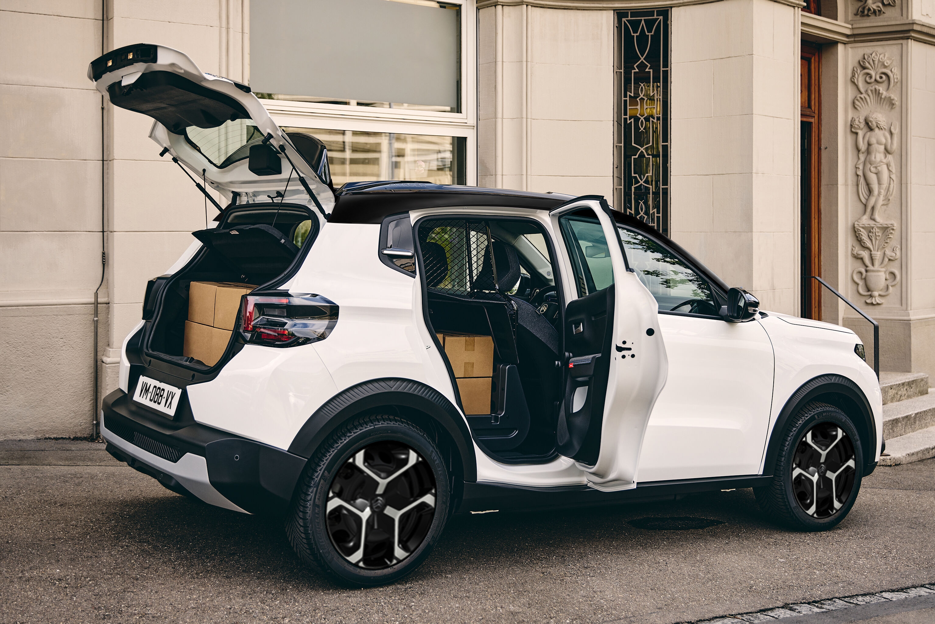 Rear three-quarter view of the Citroën ë-C3 Van with the tailgate and passenger door open, highlighting cargo accessibility, versatile loading solutions and SUV-inspired styling.